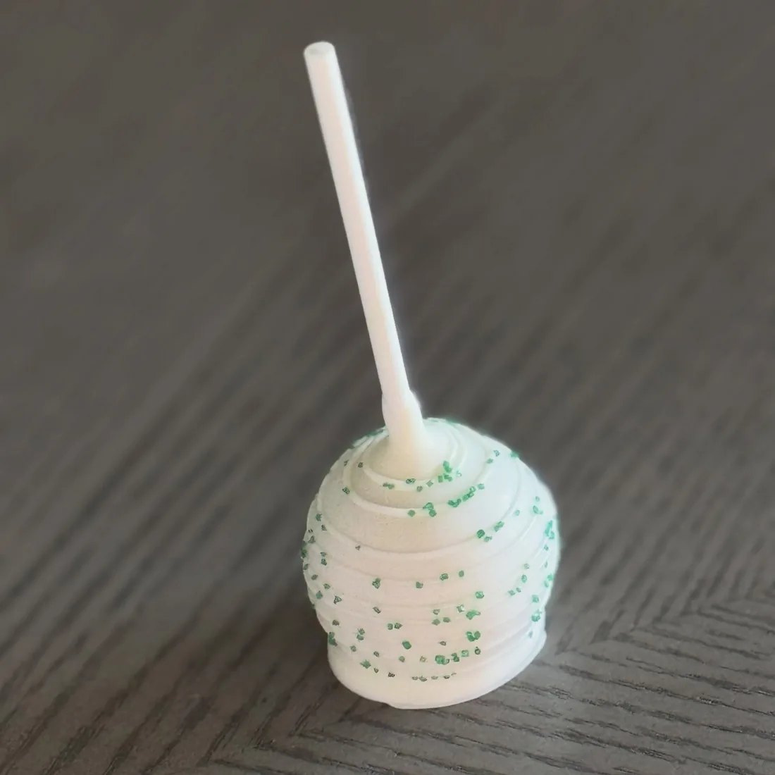 White chocolate cake pop speckled with green confetti sprinkles