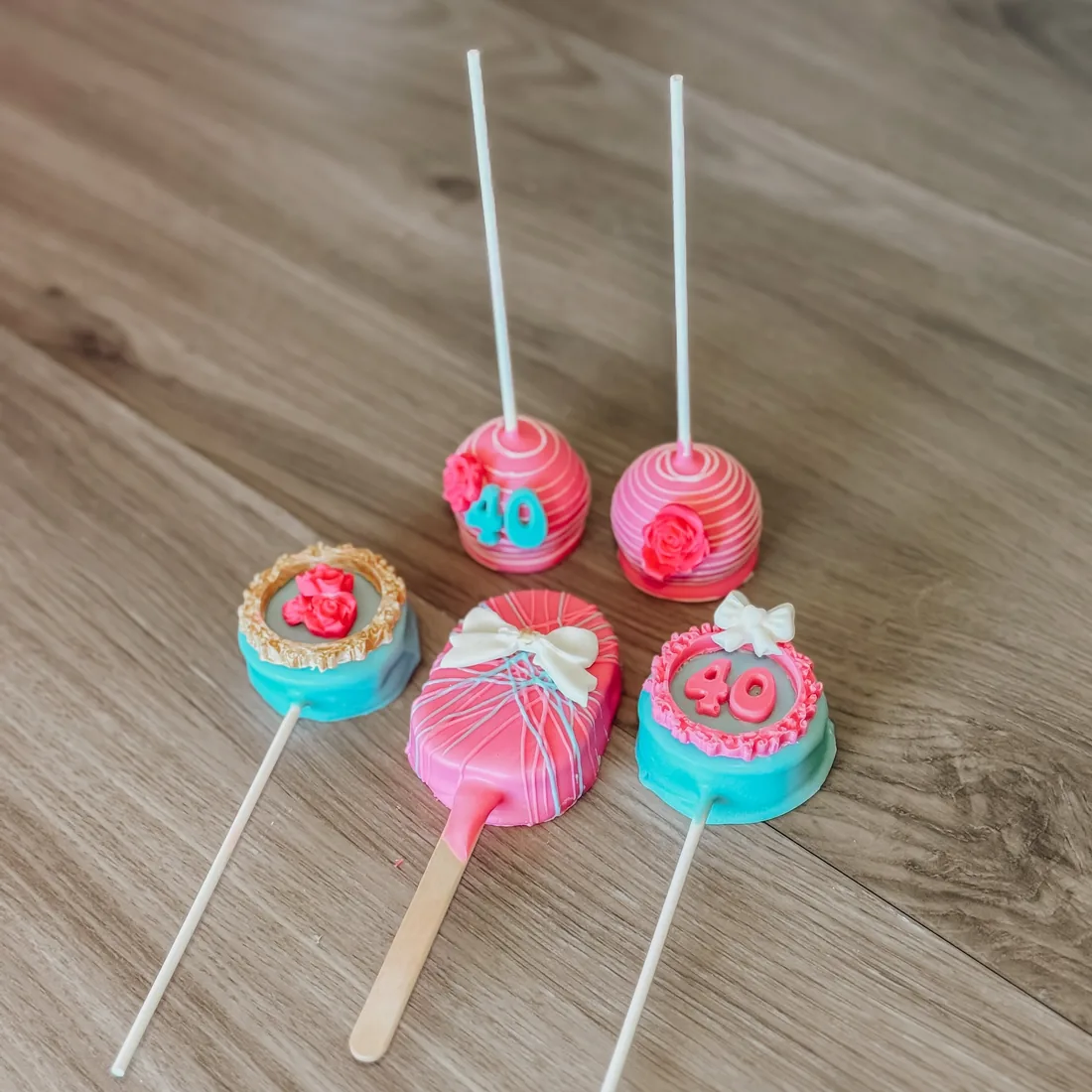 Set of pink and teal 40th birthday cake pops with bows and piped roses