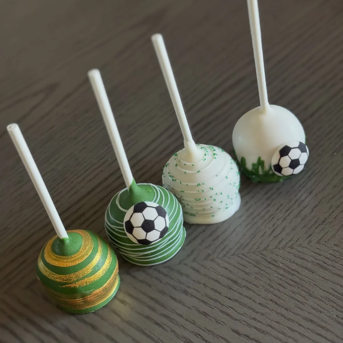 Four soccer themed cake pops in green, gold and white team colors