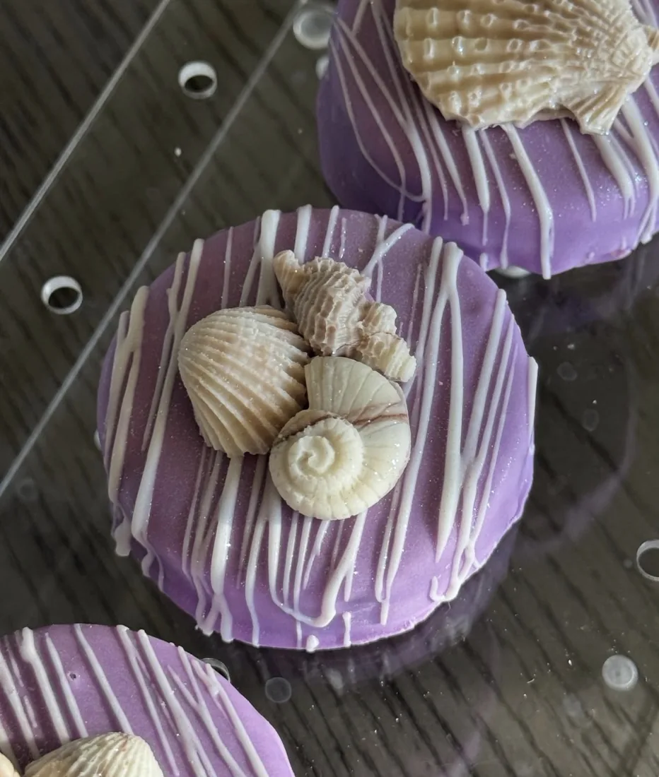 Purple dipped cake pucks topped with clusters of white chocolate seashells