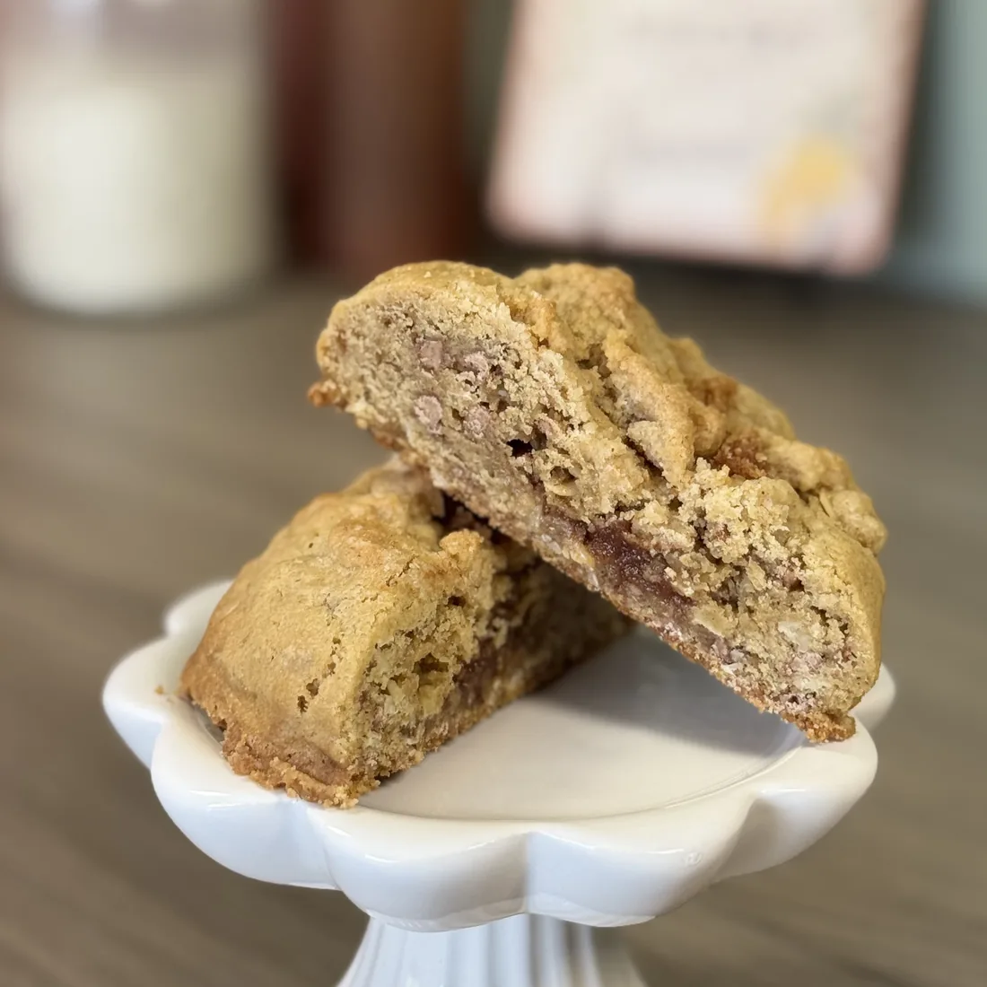Apple cobbler cookie split in half on a white pedestal stand, showing a layer of apple butter through the middle
