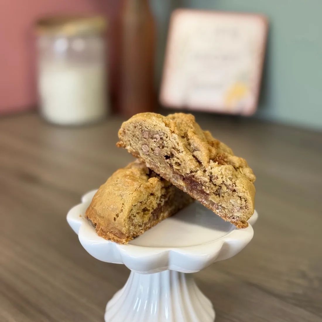 Apple crisp cookie split in half on a white pedestal stand, showing an apple butter core through the middle