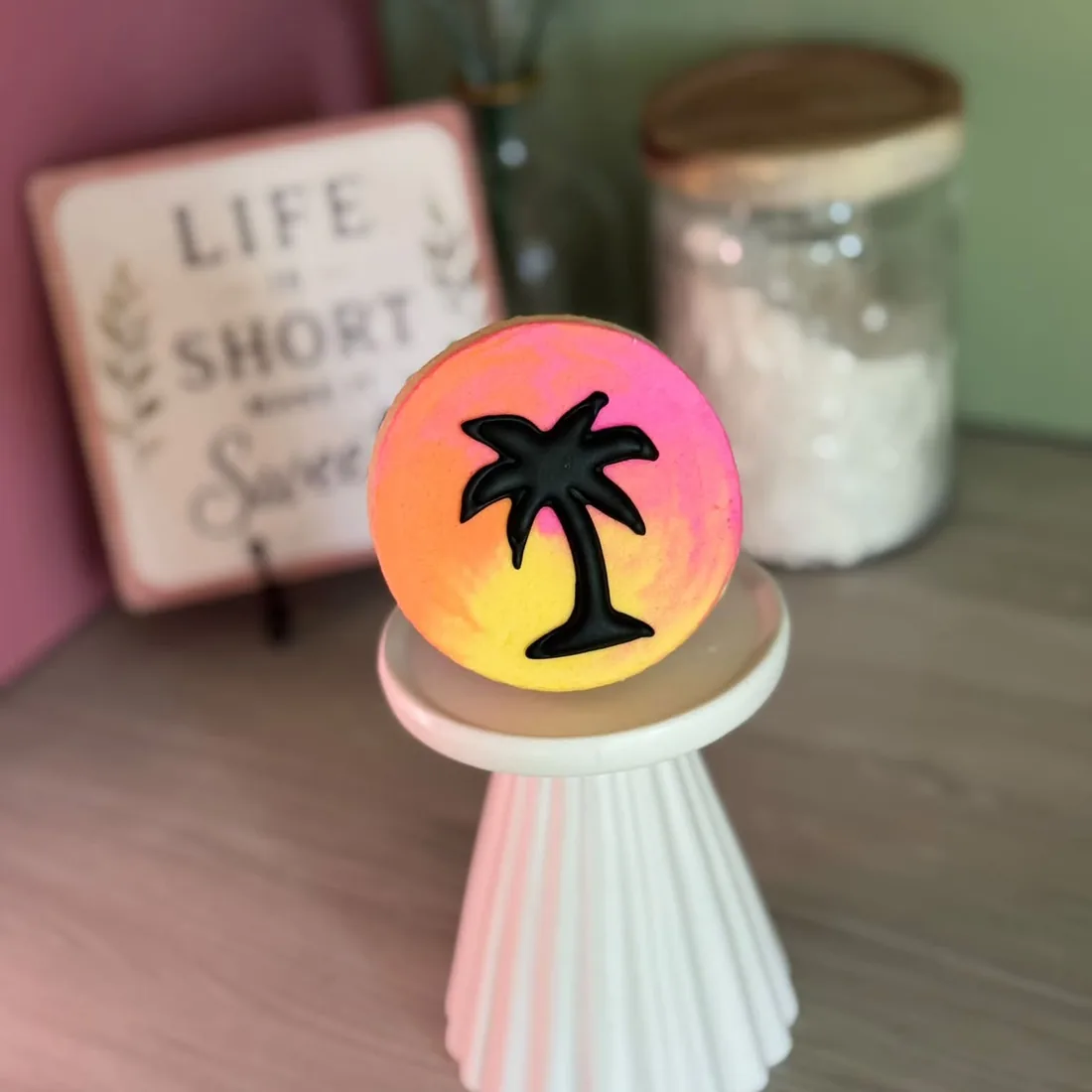 Round cookie with a black palm tree silhouette over a pink and orange sunset