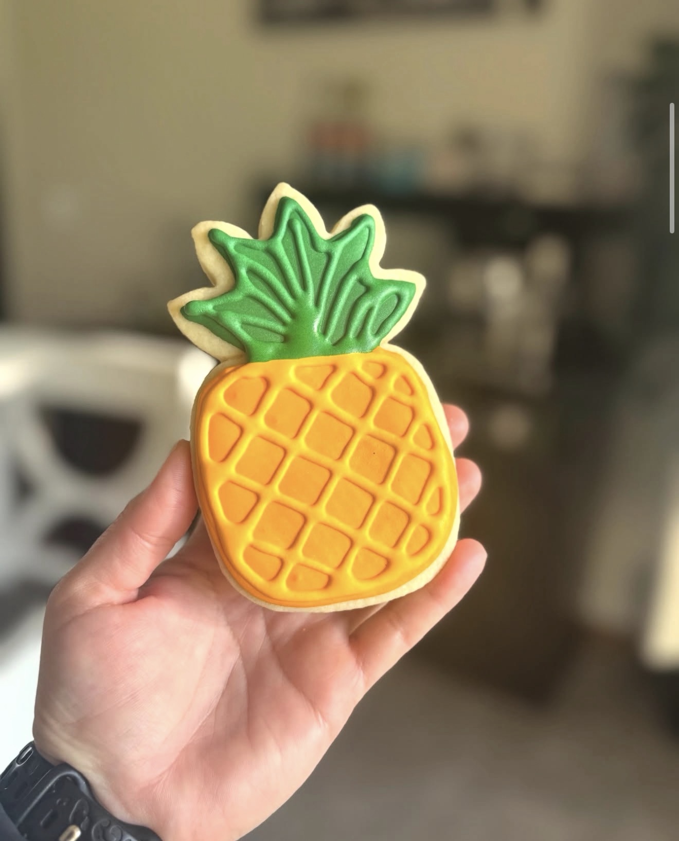 Pineapple shaped decorated sugar cookie with yellow and green royal icing
