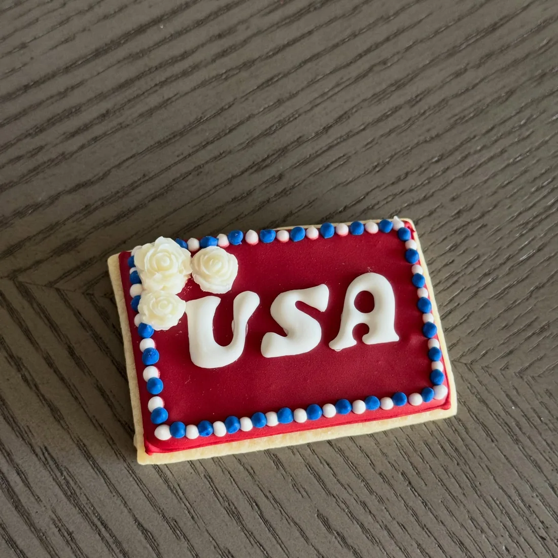 Red rectangle cookie with white USA lettering and piped white roses