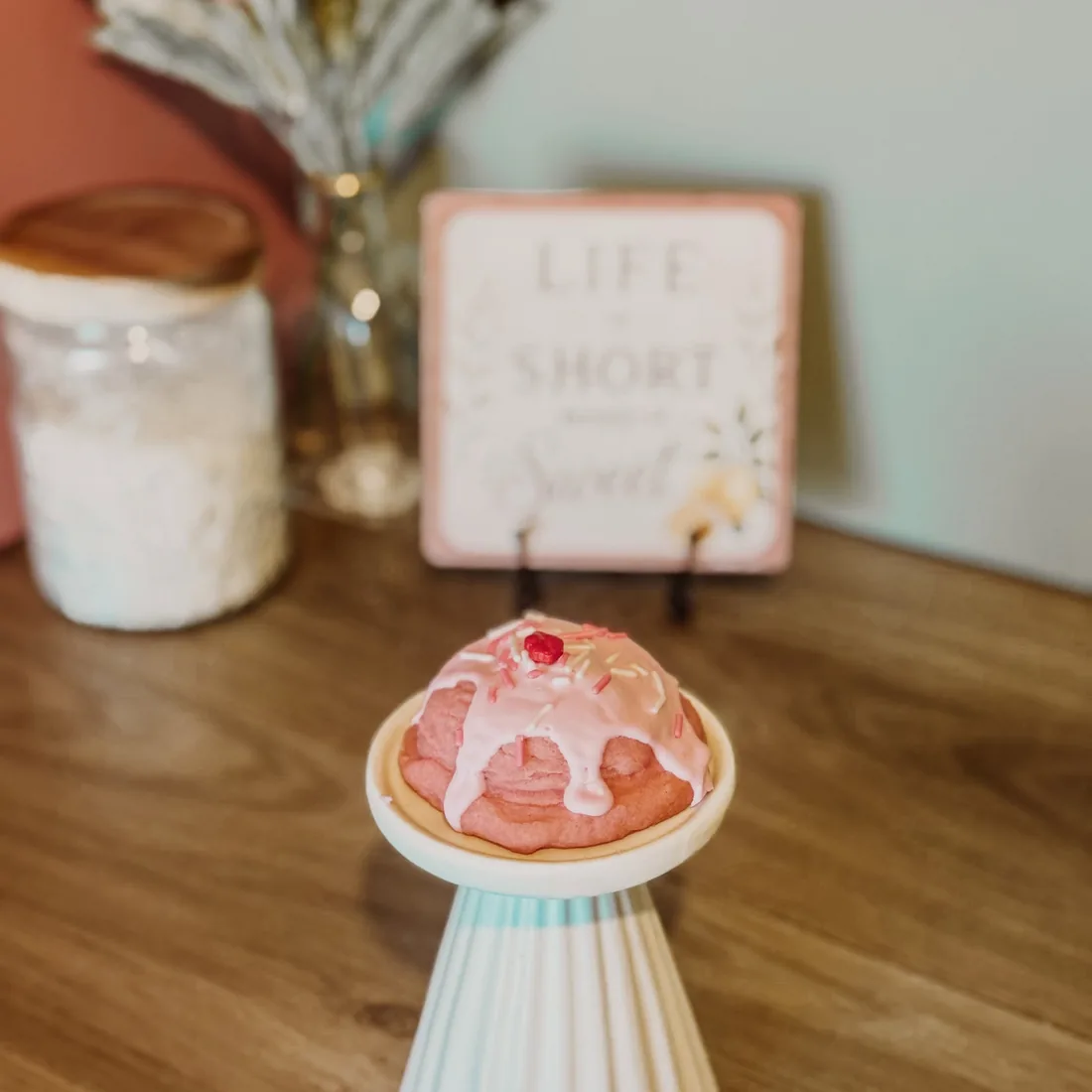 Vanilla ice cream cookie with pink glaze and a cherry on top