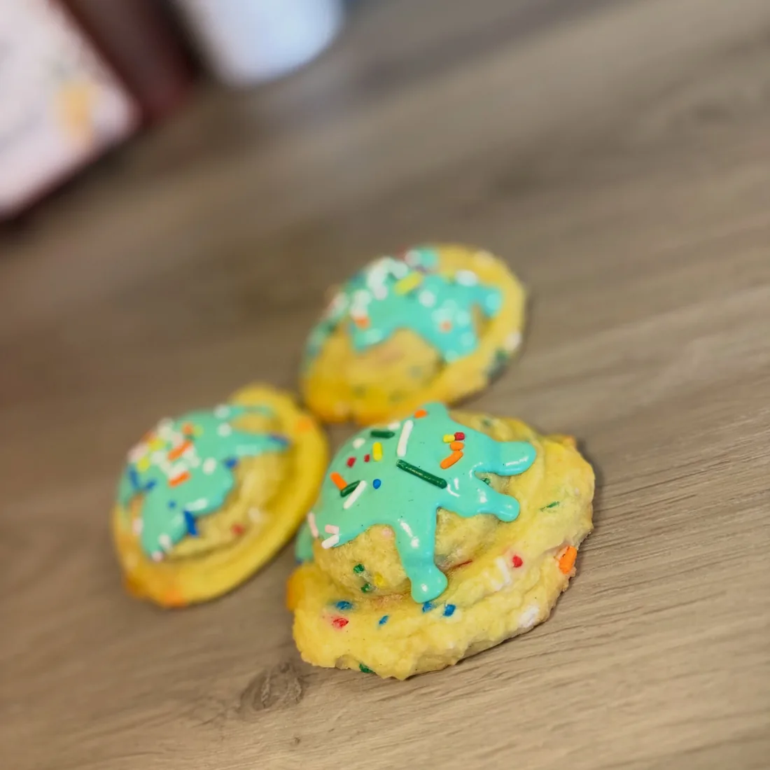 Thick birthday cake cookies packed with sprinkles and white chocolate chips under a turquoise birthday cake batter glaze
