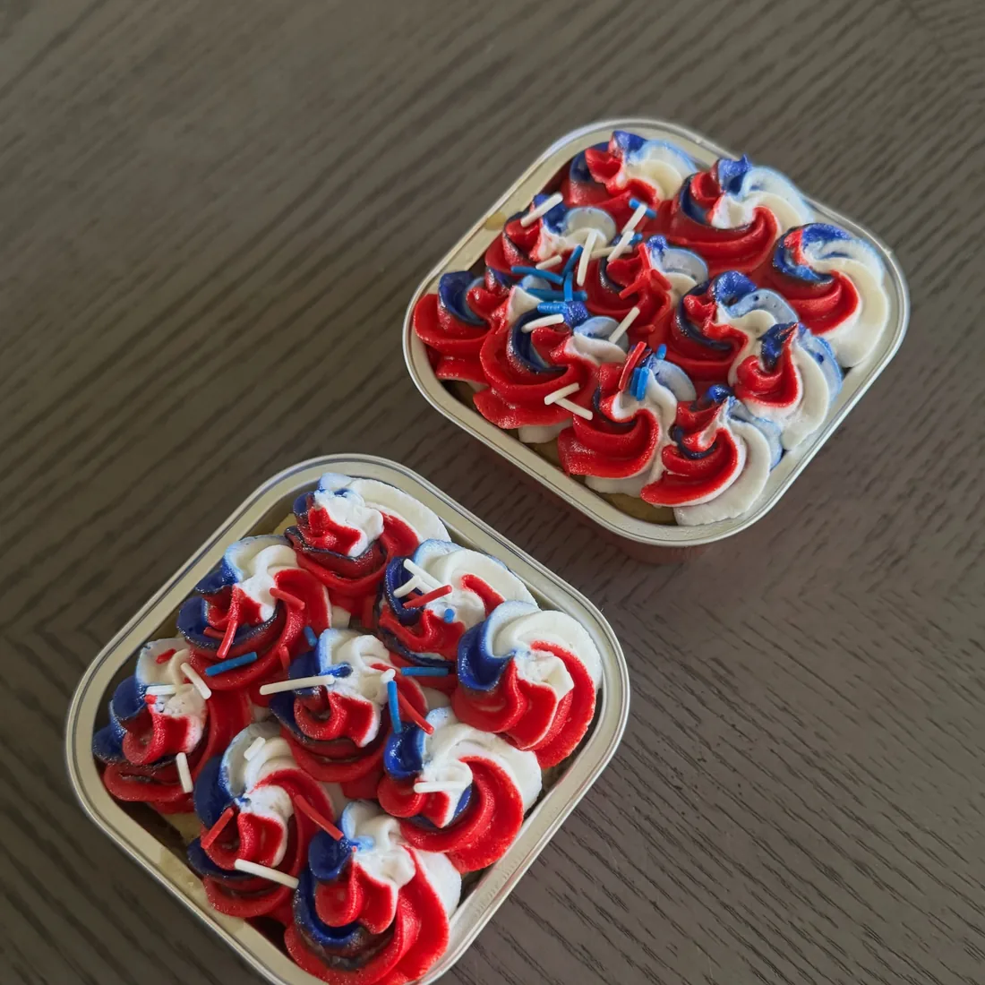 Two mini cakes covered in red, white and blue buttercream rosettes in square containers