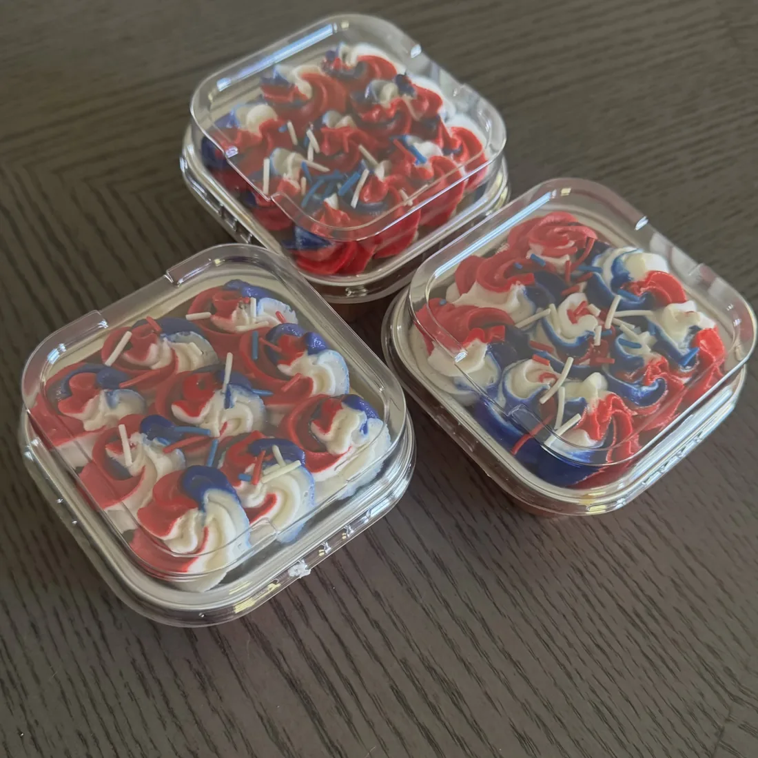 Three mini cakes covered in red, white and blue buttercream rosettes in square containers