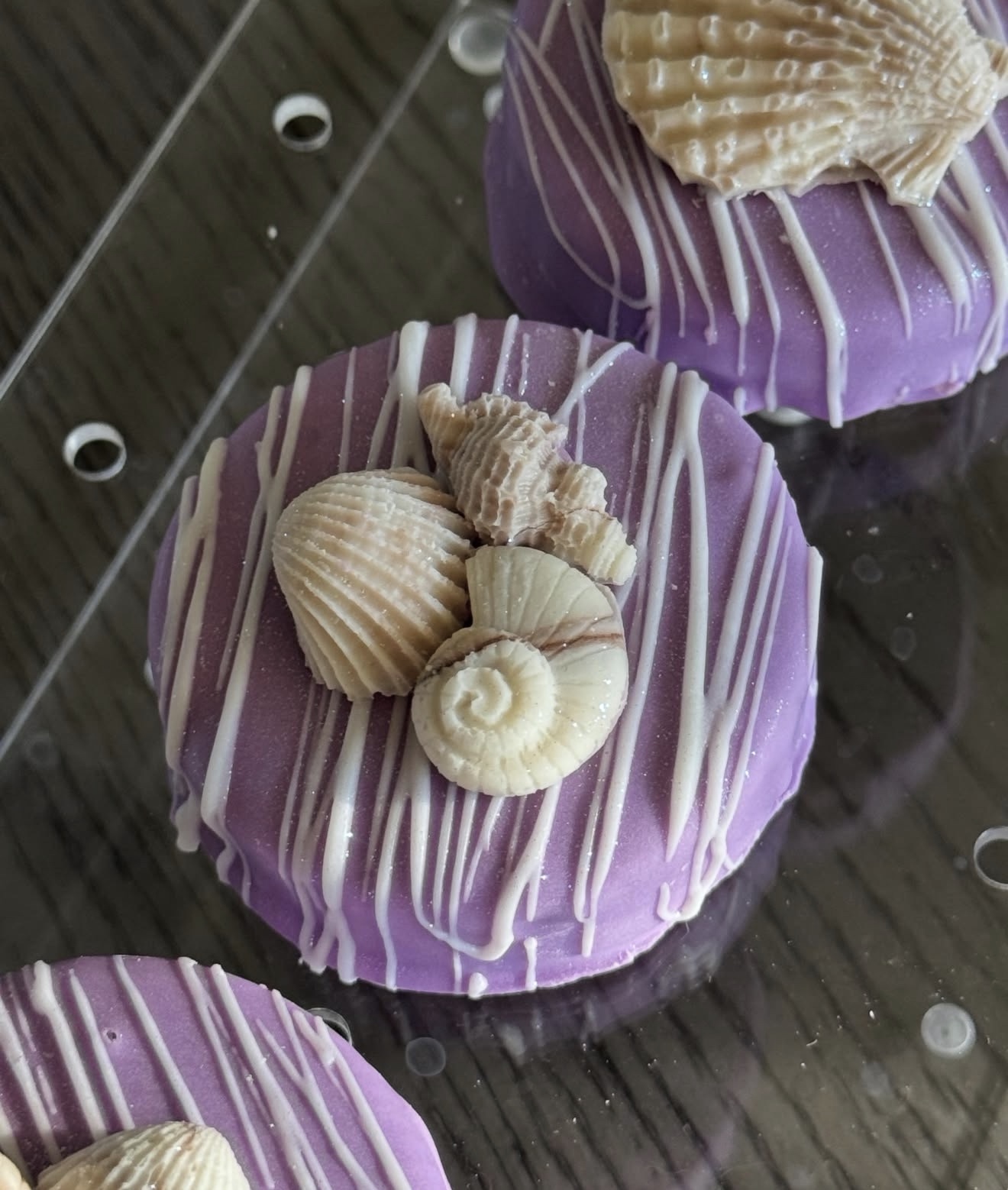 Purple dipped Oreo with snail, scallop, and shell cluster topper held in hand