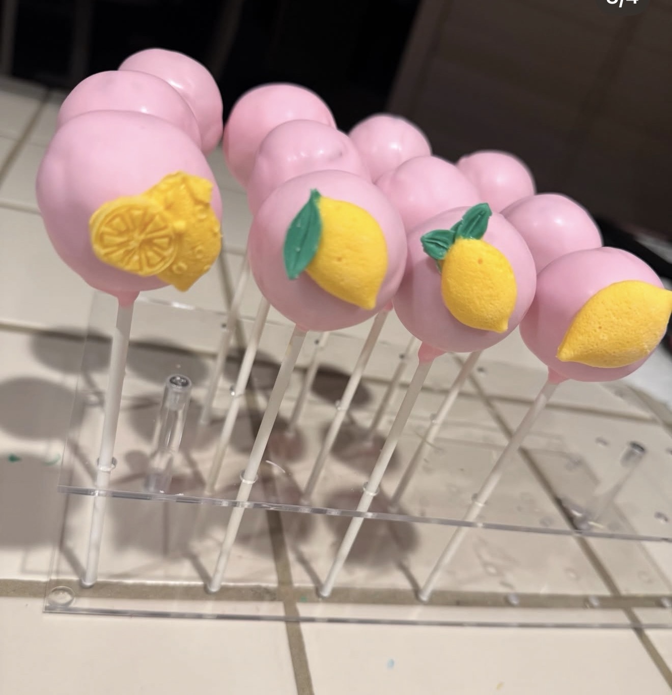 Pink lemon cake pops on acrylic stand with yellow lemon and lemon slice toppers