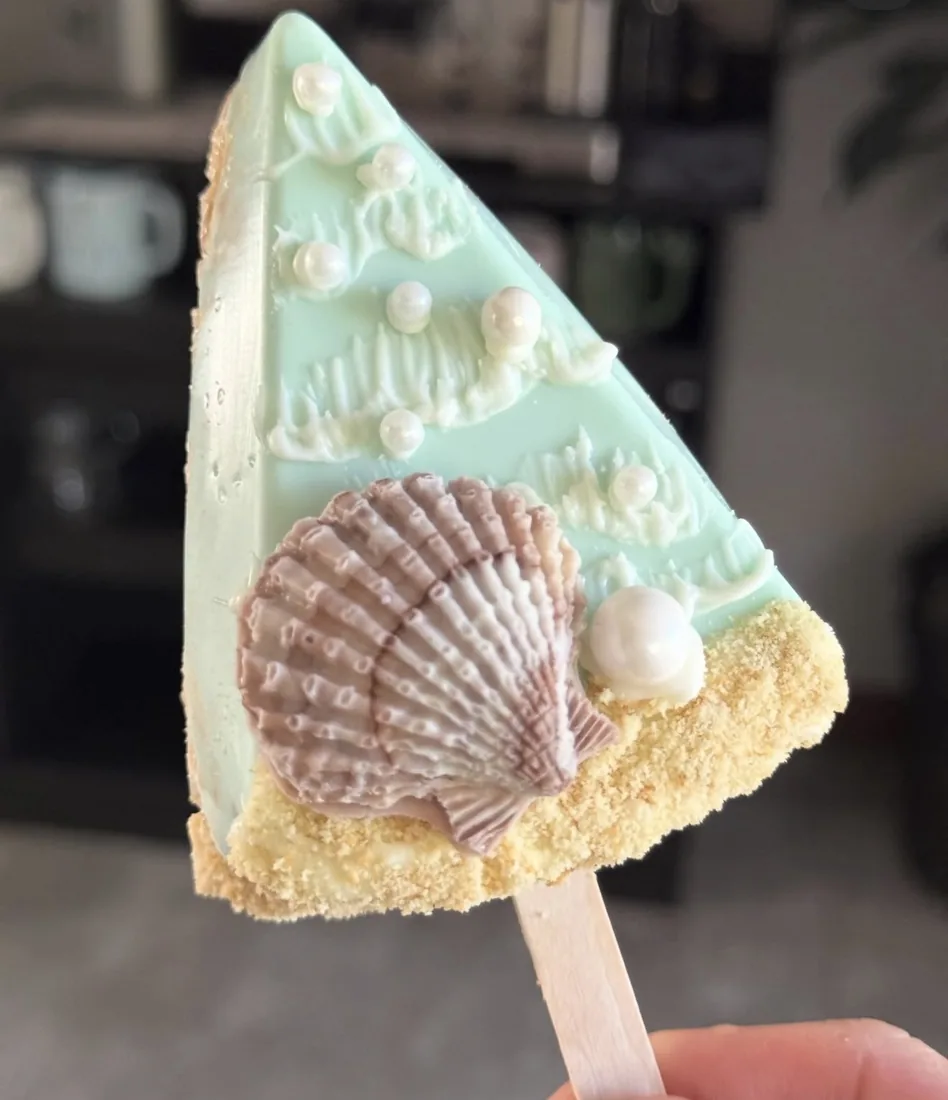 Mint green Rice Krispie treat topped with a large scallop shell and a sugar pearl
