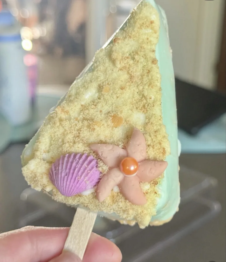 Rice Krispie Treat topped with sandy crumble, a purple scallop shell and pink coral